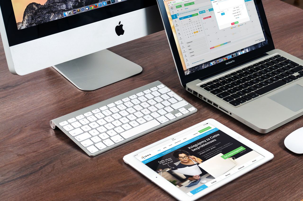 Un bureau de travail élégant mettant en avant des appareils Apple : iMac, MacBook et iPad.