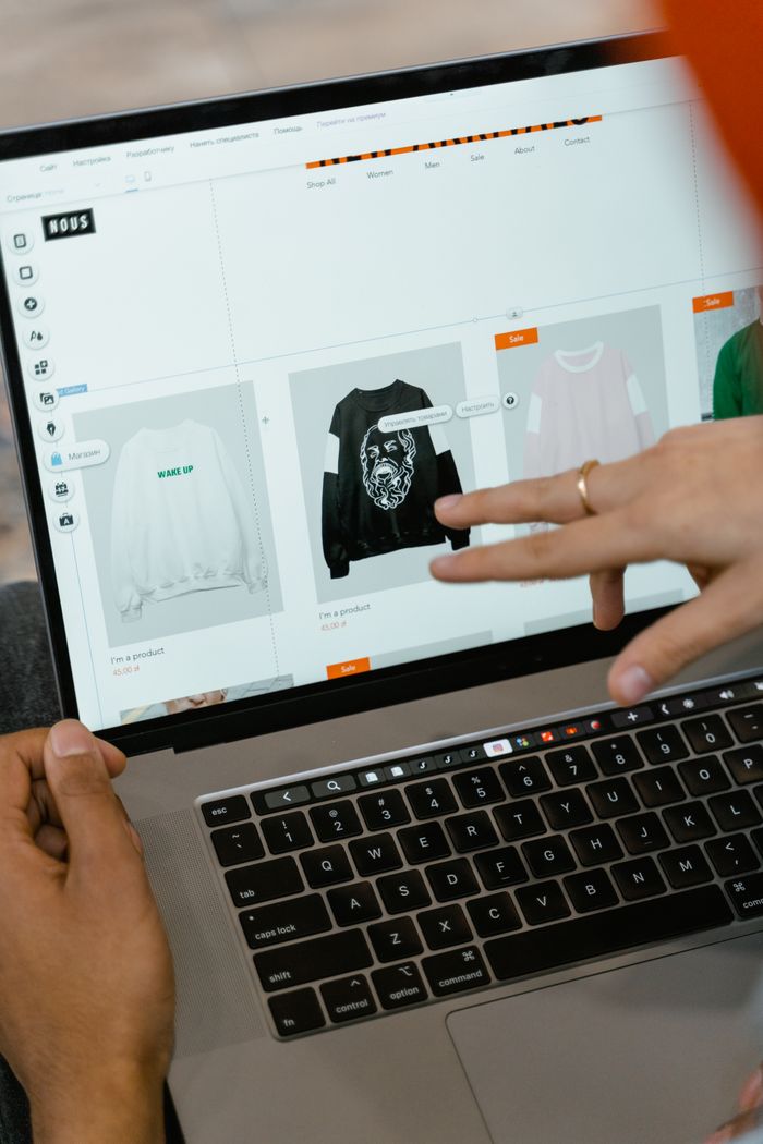 Vue rapprochée de mains utilisant un site e-commerce sur l’écran d’un ordinateur portable, en intérieur.